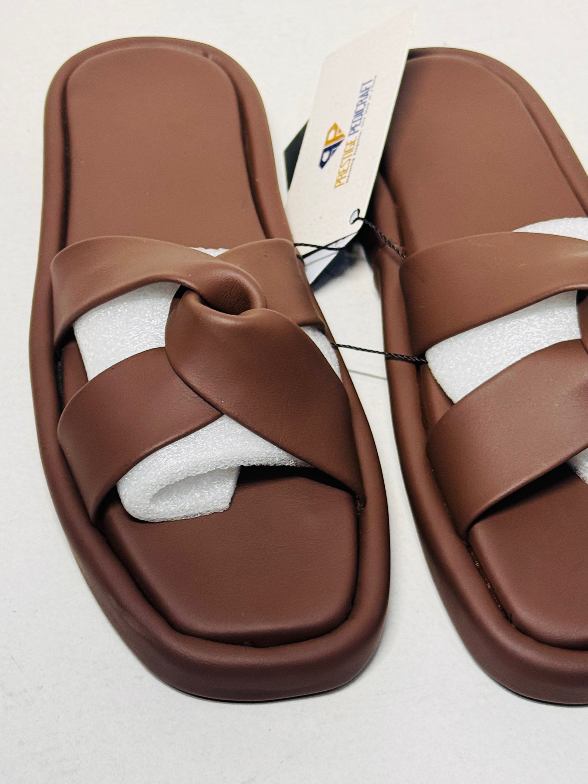 Pair of brown sandals with a white sole on a light gray background